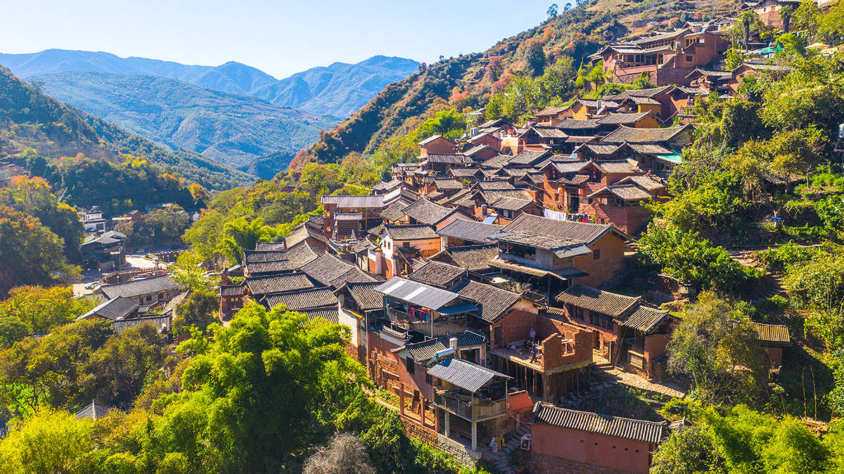 Panoramic view of Nuodeng Ancient Village, showing Bai ethnic ancient buildings built on mountains with winding stone paths