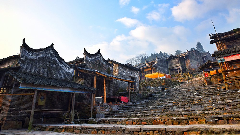 Stone paths and traditional architecture in Liannan Yao Village, villagers working in front of their homes